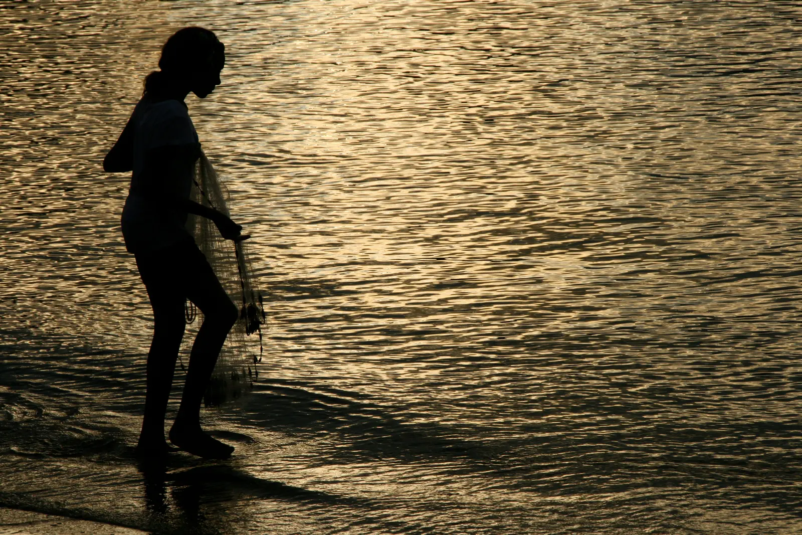A figure walking on golden water at sunset