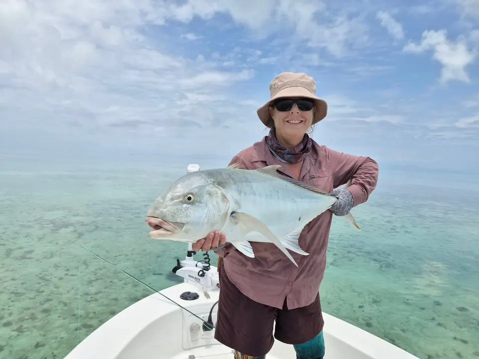 An angler holding a giant trevally on the reef flats