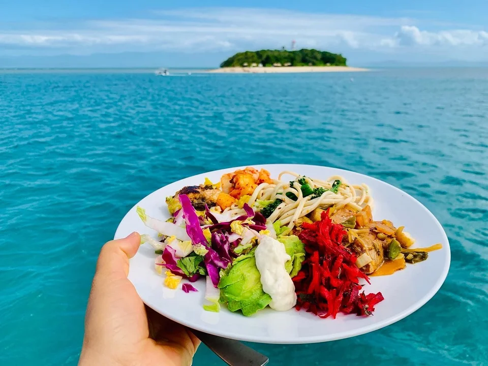 A plate of food held above turquoise water