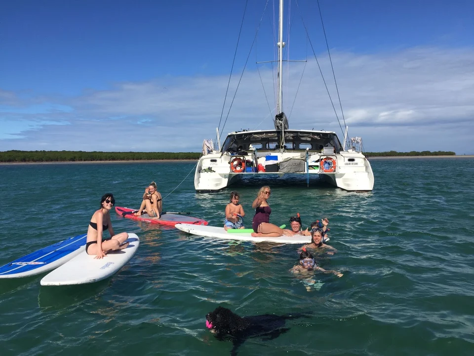 Guests on paddleboards behind the yacht