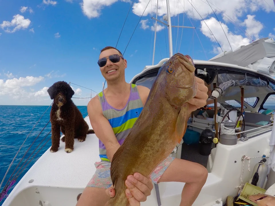 A guest holding a fish on deck