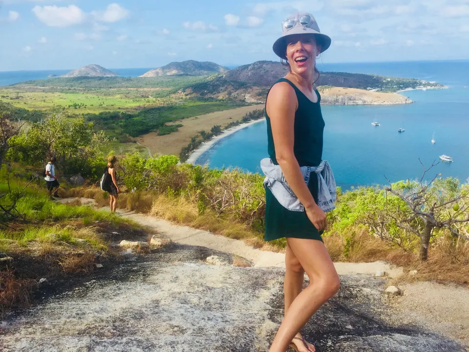 A guest on a hilltop walk above a sheltered island bay